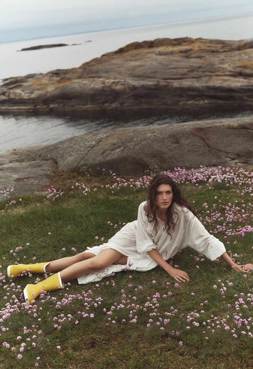A woman rests in a flower meadow with her feet in classic Viking Seilas rubber boots