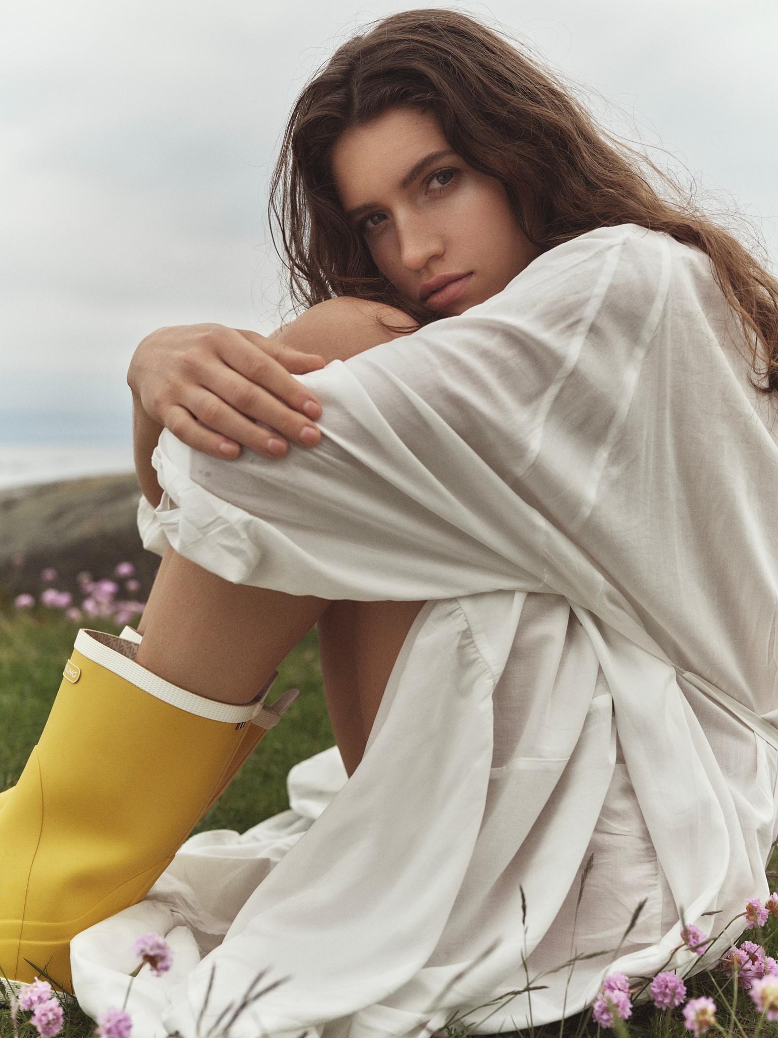 A woman rests in a flower meadow with her feet in classic Viking Seilas rubber boots